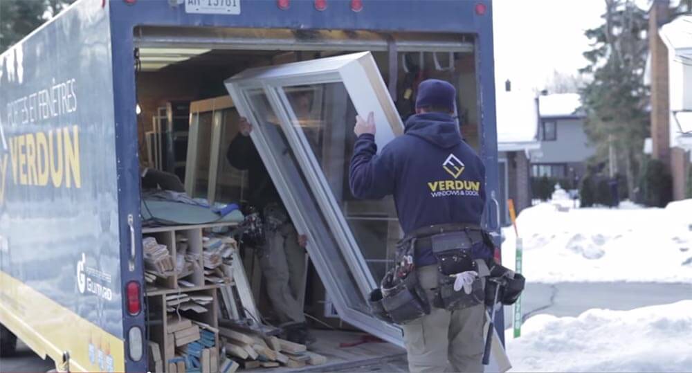 A Verdun window installer taking a replacement window out of the back of a truck in the winter time.
