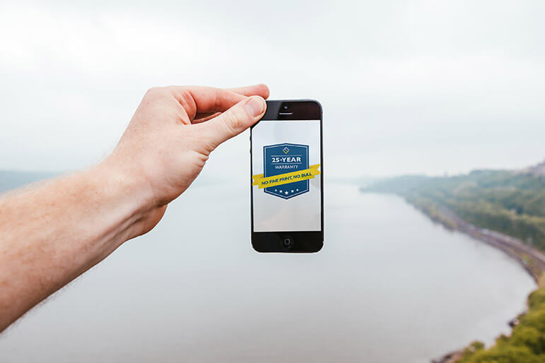 A phone is held over the horizon with an image of Verdun's new 25 year warranty.