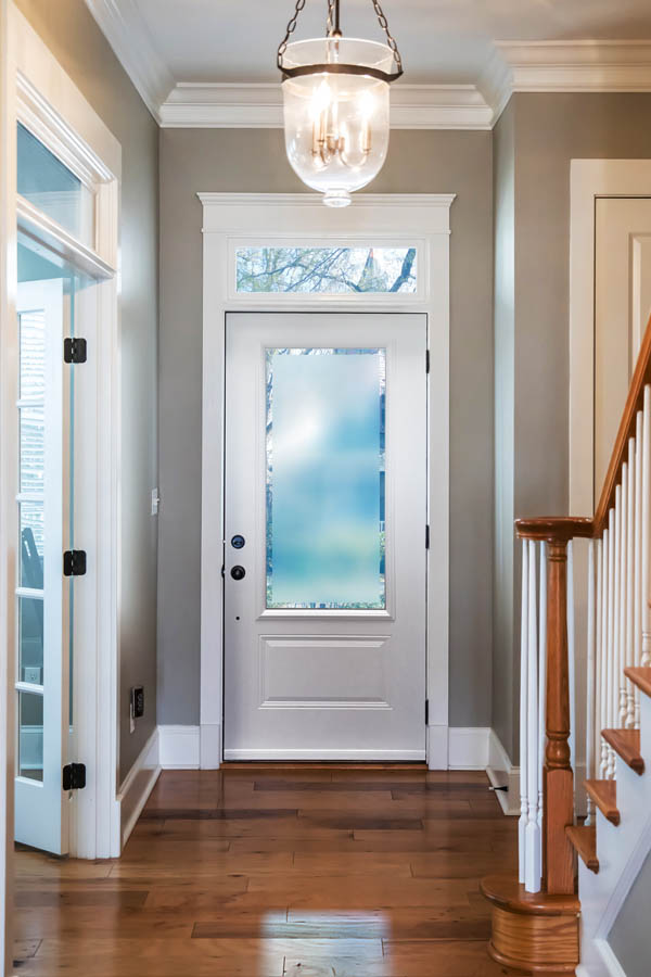 Une belle porte d'entrée blanche avec des inserts en verre Clear-Border sur une dalle de porte Orleans.