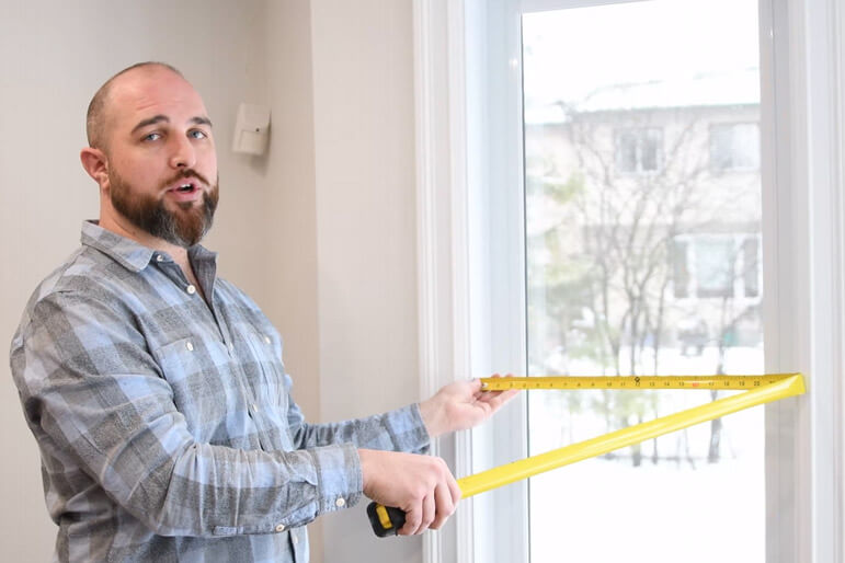 A Verdun sales representative shows holds a measuring tape to measure a window.