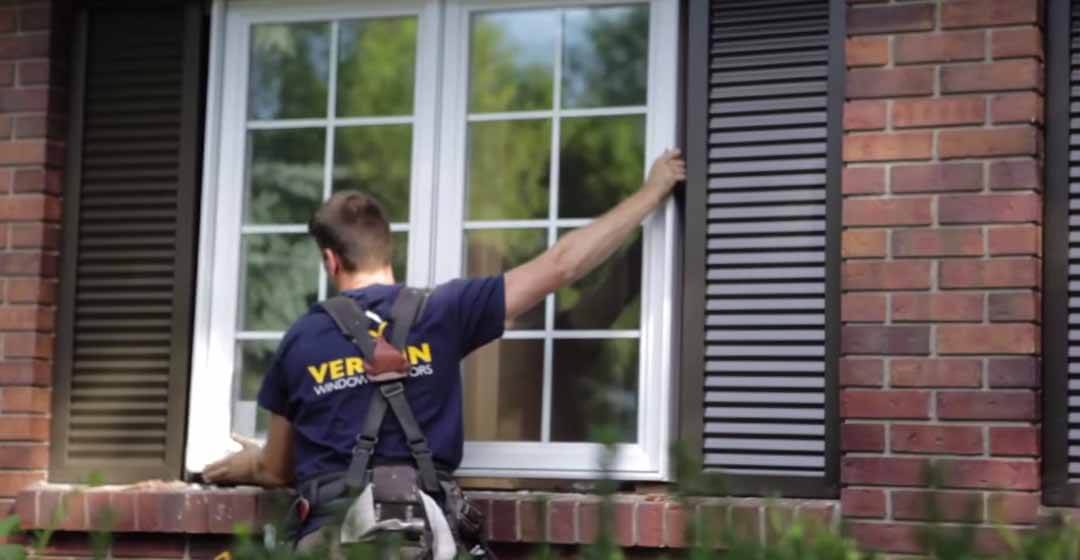 Un installateur de fenêtres de Verdun mettant en place une fenêtre à battant en PVC blanc de remplacement