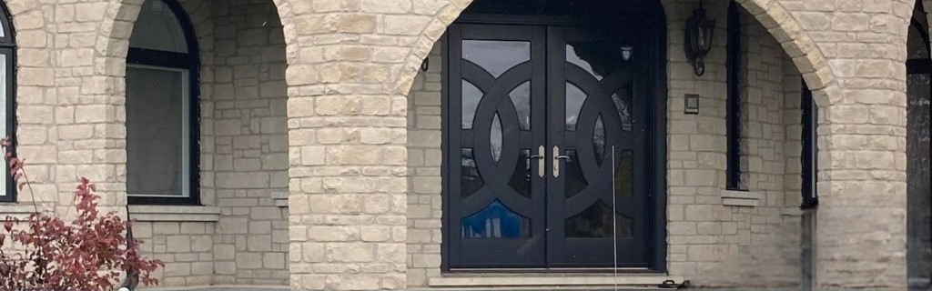 Black double front doors with decorative glass on a stone house