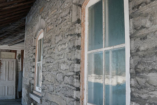 Une vieille fenêtre au rez-de-chaussée d'une maison d'époque à Crysler, en Ontario, avant son remplacement par Verdun Windows and Doors.