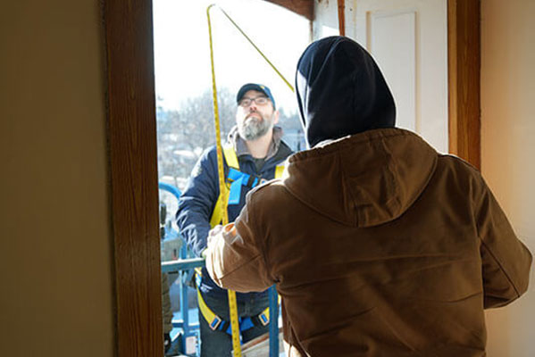 Two Verdun installers mesaure the hole in the home where a replacement window will be installed.