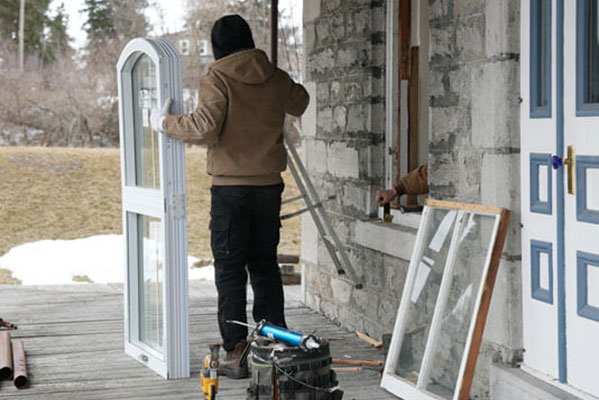 An installer prepares to put a shaped window into a vintage home.