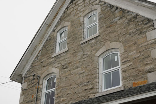An exterior view of newly renovated windows of the top storey of a vintage home.