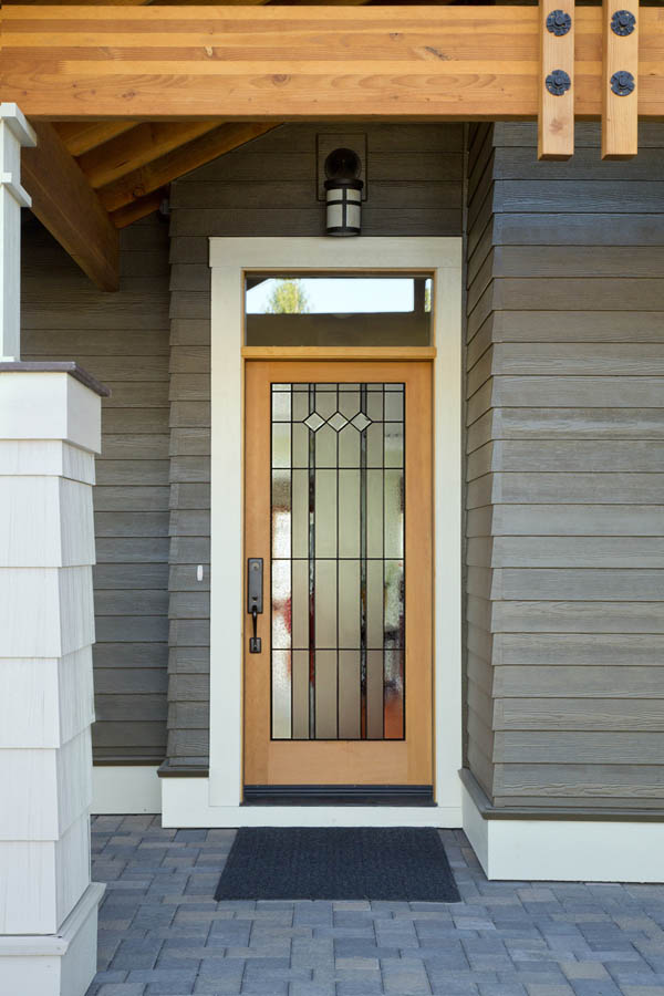 Une porte d'entrée beige avec des inserts en verre Auburn sur une dalle de porte en fibre de verre.