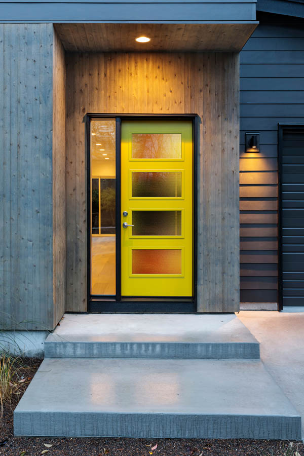 Une porte d'entrée moderne et jaune avec des inserts en verre velours côtelé sur une dalle de porte plate.