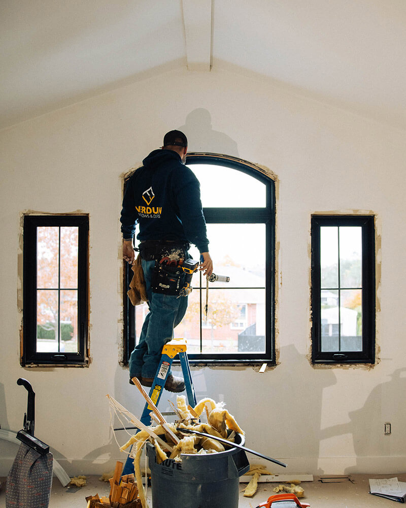 Verdun window installer puts a black casement window with top semi-circle transom in. The window has interior black paint.